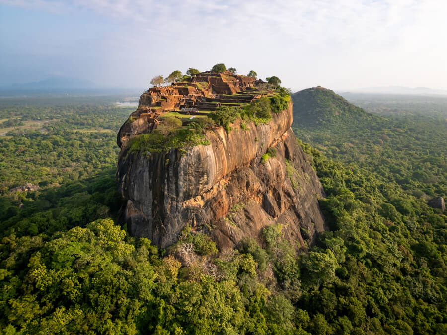 A drone shot taken above Sigiriya Rock amidst dense green vegetation, a must-visit place in any Sri Lanka itinerary.