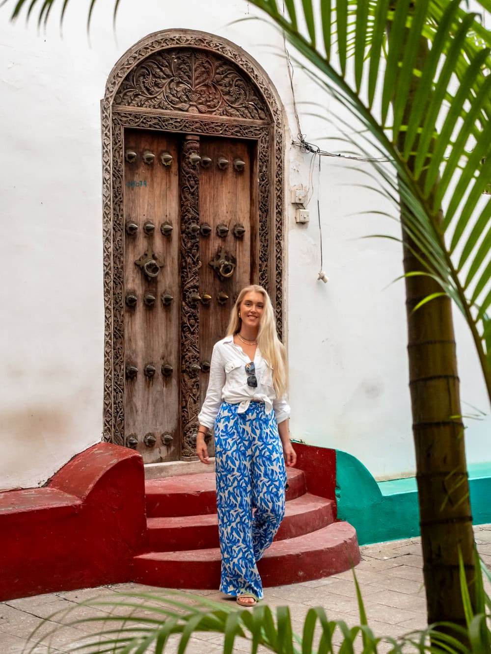 Me standing in front of an old wooden  door with intricate carvings at Stone Town.