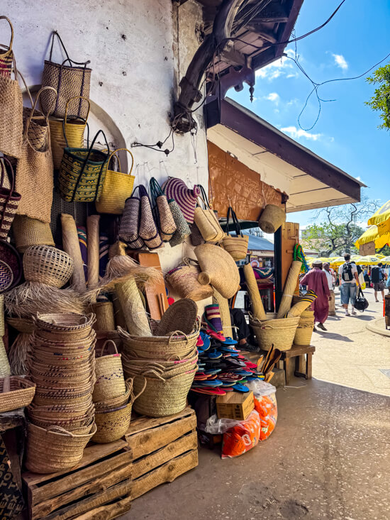 A market stall displaying various baskets and bags made of straw at a market in Stone Town.