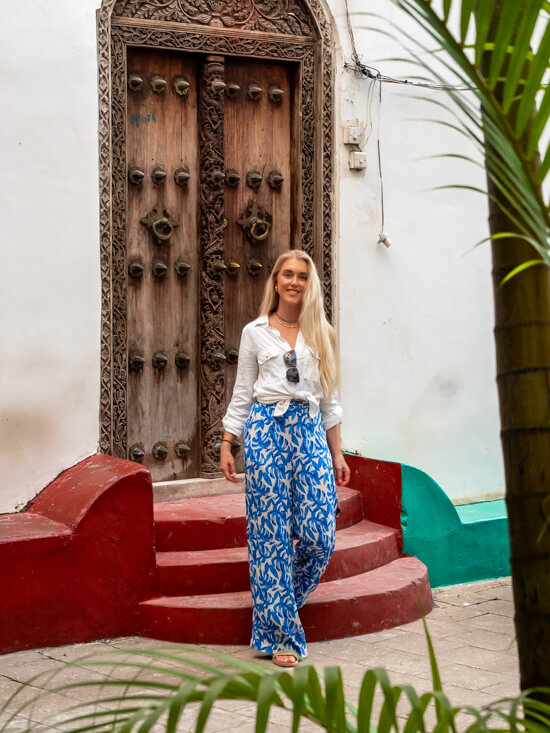 Me standing in front of an old wooden  door with intricate carvings at Stone Town.