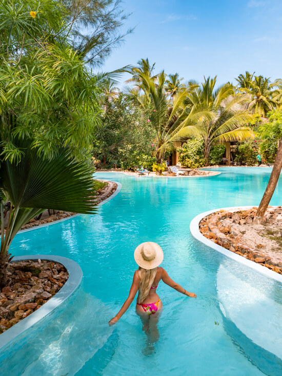 Me standing in the large turquoise pool of The Nest Hotel amidst tropical plants.
