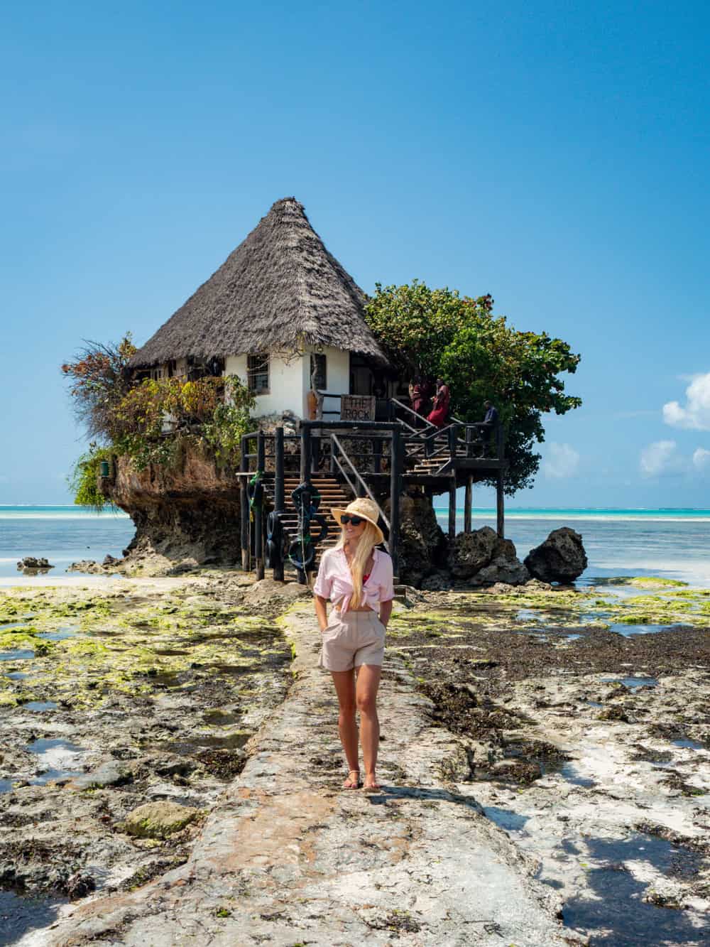 Me standing in front of a small restaurant built on top of a rock jutting out from the sea bed.