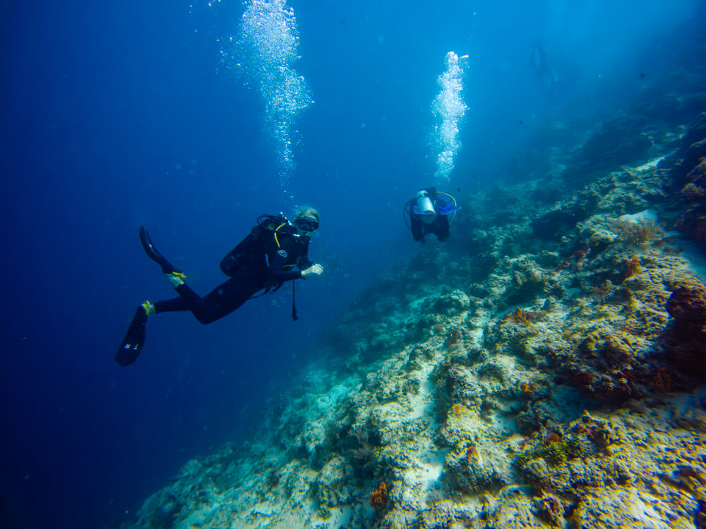 Me scuba diving next to a large sloping reef at Mnemba Atoll, one of the top things to do in Zanzibar.