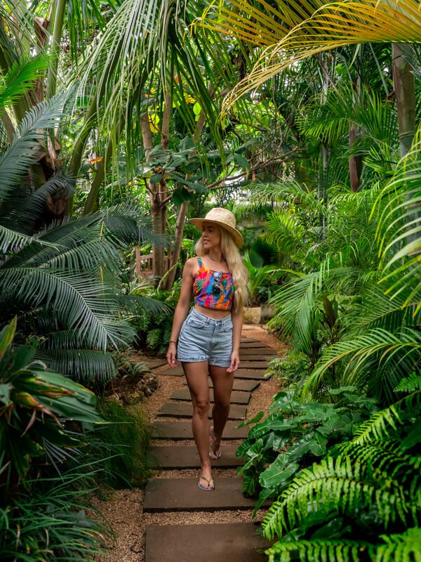 Me walking on a pathway surrounded by lush green plants at our hotel in Nungwi.