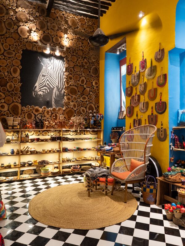 A souvenir shop with colorful walls displaying various handicrafts made of straw and wood.