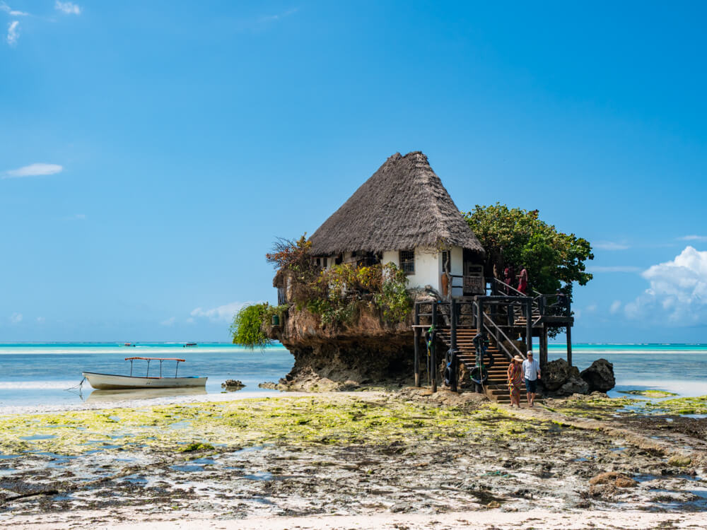 The Rock Restaurant with a straw roof and white walls, built on top of a large rock jutting out from the sea bed on Pingwe Beach.