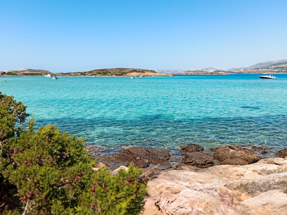 A beach with turquoise water and a rocky shore on the island of Antiparos in Greece.