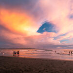 A sky full of orange and pink clouds and a black sand beach during sunset in Santa Catalina, Panama