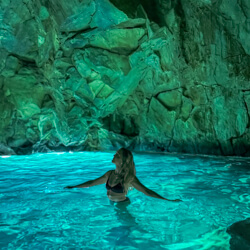 Me standing in glowing turquoise waters inside a sea cave in Albania.