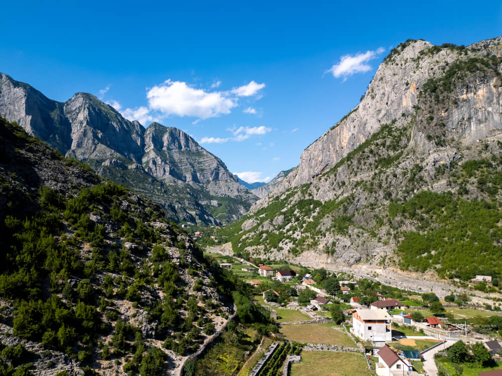 The dramatic limestone peaks of the Accursed Mountains surrounding a green valley in Tamare in northern Albania.